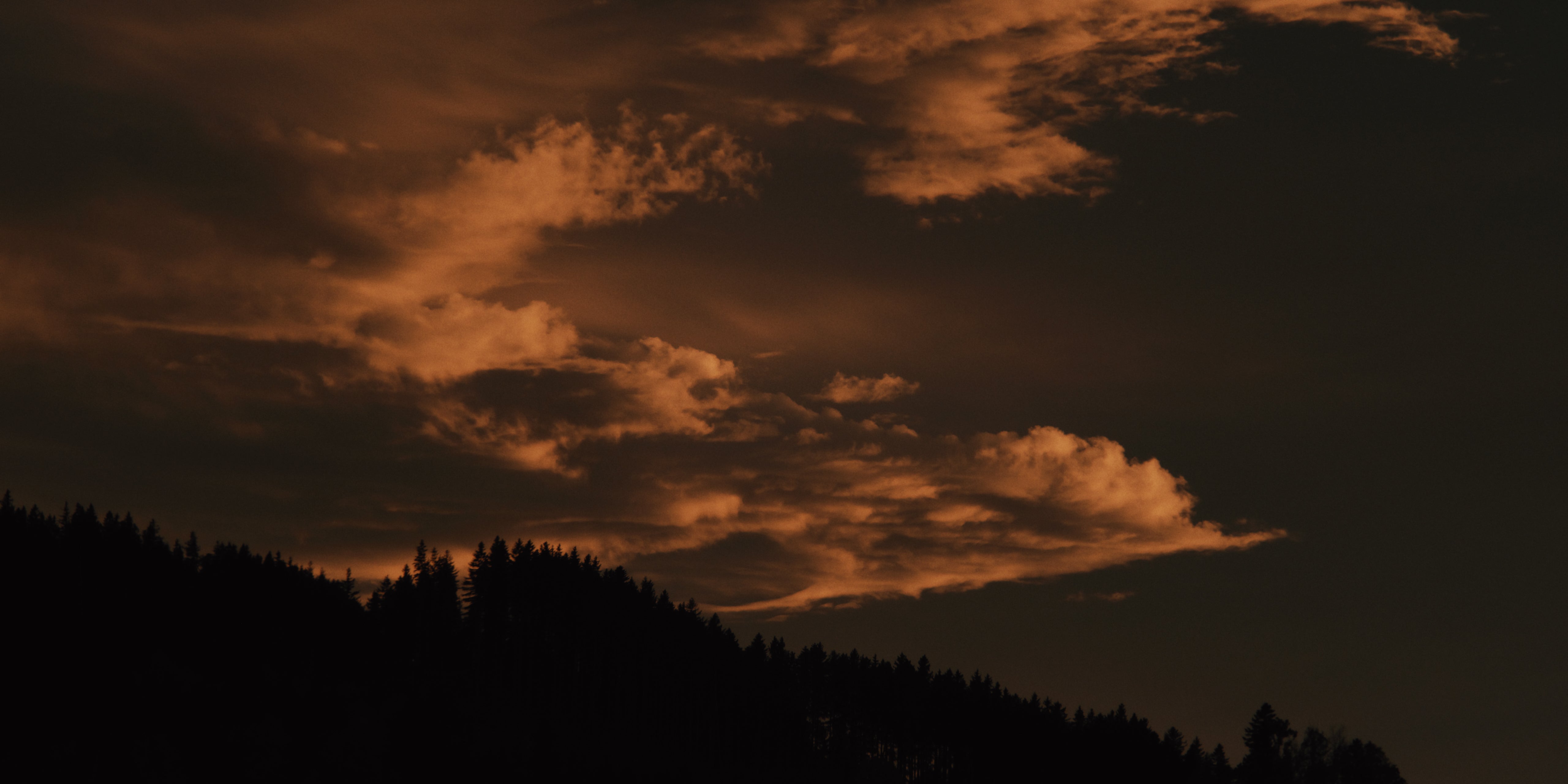 Dämmerung mit Blick über Ostschweizer Hügel und leicht erleuchtete Wolkenstreifen am Himmel